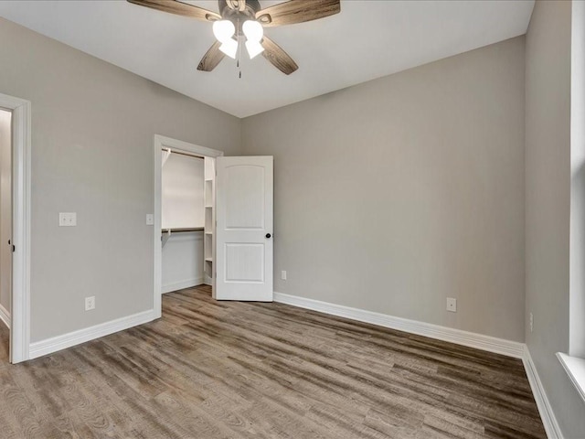 unfurnished bedroom with hardwood / wood-style flooring, ceiling fan, a spacious closet, and a closet