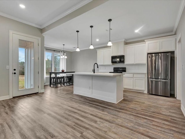 kitchen featuring crown molding, black appliances, hanging light fixtures, an island with sink, and white cabinets