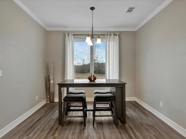 dining room with an inviting chandelier, crown molding, and dark hardwood / wood-style flooring