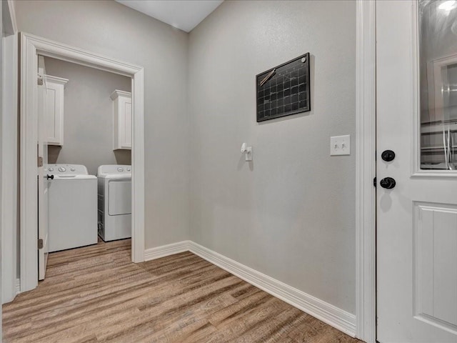 laundry room featuring cabinets, independent washer and dryer, and light hardwood / wood-style flooring