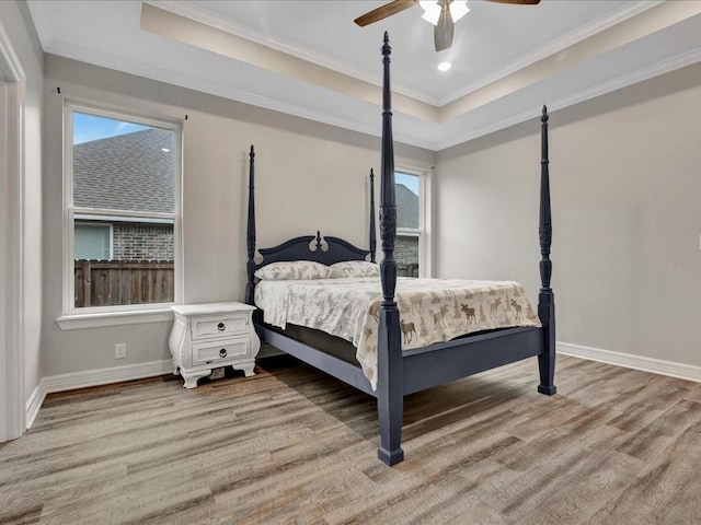 bedroom featuring crown molding, ceiling fan, a raised ceiling, and light hardwood / wood-style floors