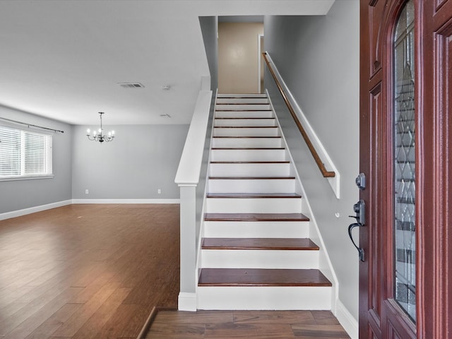 stairway featuring wood-type flooring and a chandelier