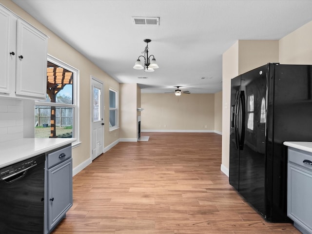 kitchen featuring white cabinets, backsplash, hanging light fixtures, light hardwood / wood-style floors, and black appliances