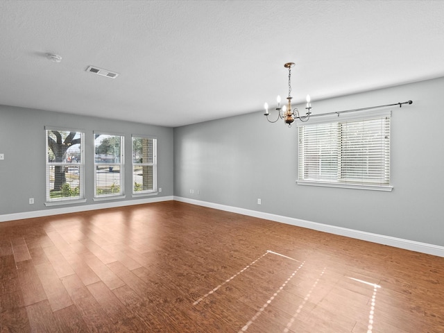 unfurnished room featuring hardwood / wood-style flooring, a notable chandelier, and a textured ceiling