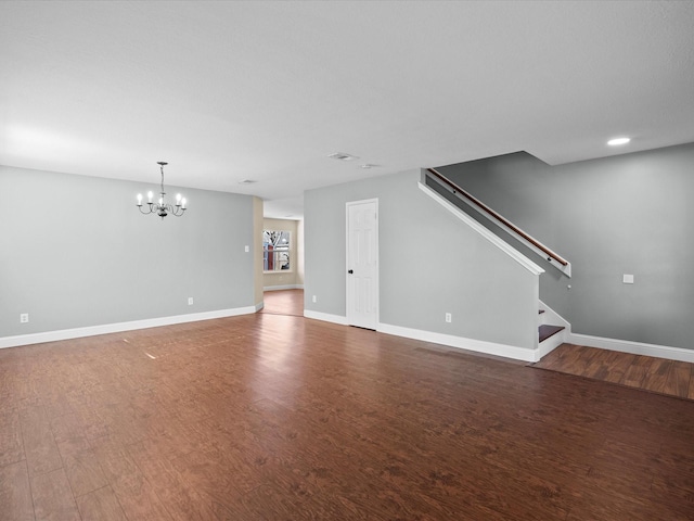 unfurnished living room featuring a notable chandelier and dark wood-type flooring