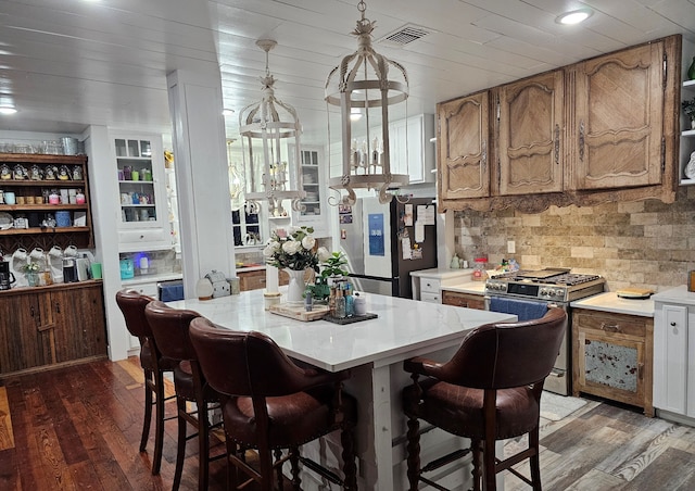 kitchen featuring light countertops, hanging light fixtures, dark wood finished floors, and stainless steel appliances