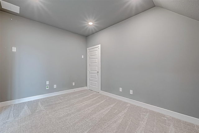 empty room featuring vaulted ceiling and carpet