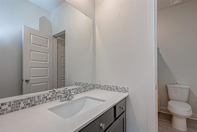 bathroom with vanity, decorative backsplash, toilet, and hardwood / wood-style flooring