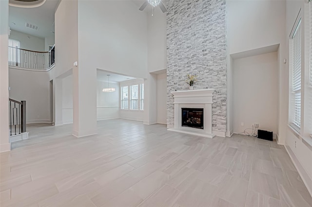 unfurnished living room with light wood-type flooring, ceiling fan with notable chandelier, and a fireplace