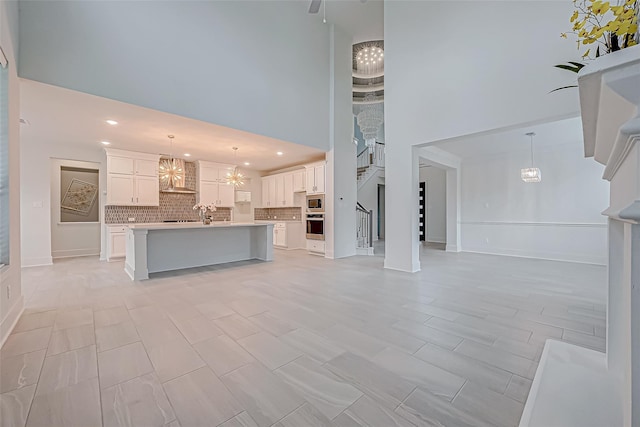 unfurnished living room featuring a notable chandelier and a high ceiling