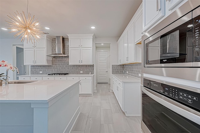 kitchen featuring white cabinetry, wall chimney range hood, stainless steel appliances, and sink