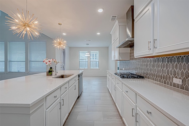 kitchen with sink, decorative light fixtures, wall chimney range hood, stainless steel appliances, and backsplash