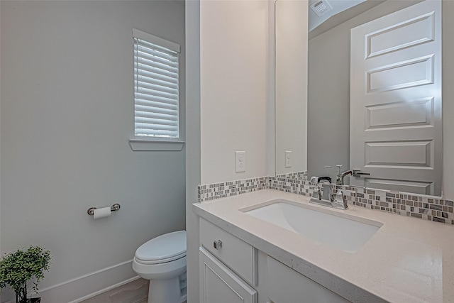 bathroom featuring vanity, decorative backsplash, and toilet