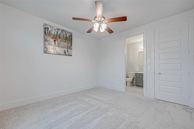 unfurnished bedroom featuring ensuite bath, light colored carpet, and ceiling fan