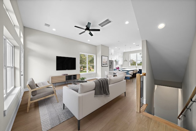 living room with a wealth of natural light, wood-type flooring, and ceiling fan