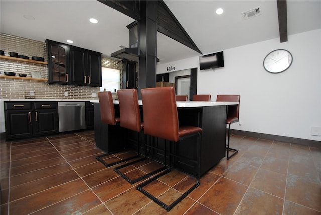 kitchen featuring a kitchen bar, vaulted ceiling with beams, tasteful backsplash, stainless steel dishwasher, and dark tile patterned flooring