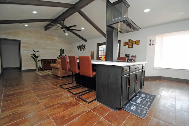 kitchen featuring ceiling fan, a healthy amount of sunlight, a kitchen bar, and lofted ceiling with beams