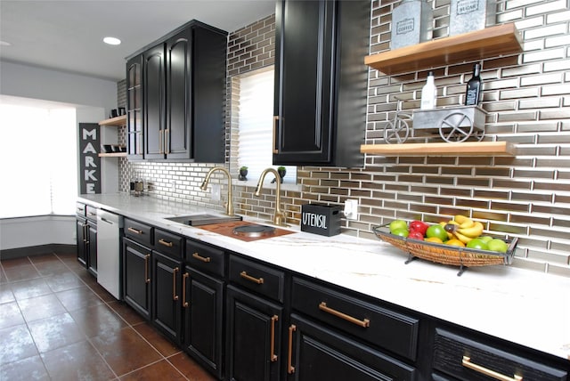 kitchen with sink, dark tile patterned floors, backsplash, light stone counters, and stainless steel dishwasher