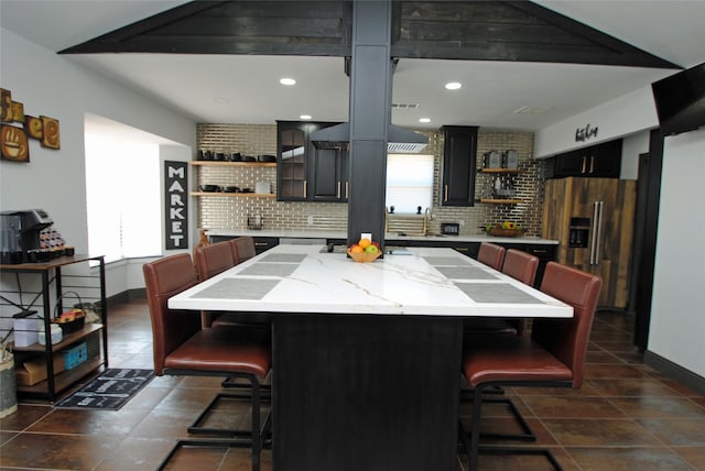 kitchen featuring a kitchen island, a breakfast bar, high end fridge, and backsplash