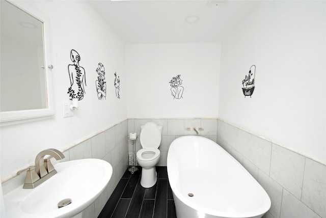 bathroom with tile walls, sink, a tub, and toilet