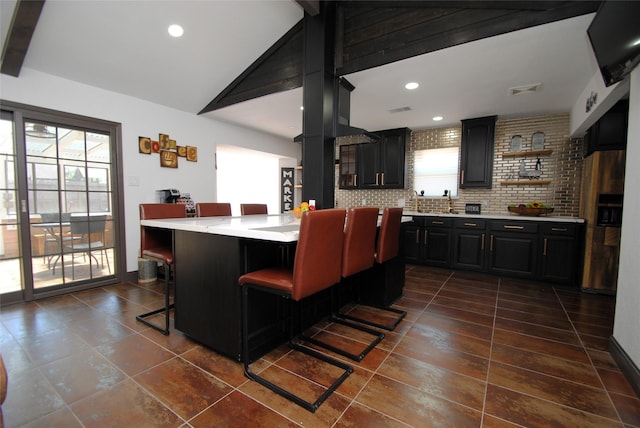 kitchen featuring tasteful backsplash, a healthy amount of sunlight, a kitchen breakfast bar, and vaulted ceiling