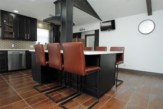 kitchen featuring a breakfast bar, dark tile patterned floors, dishwasher, vaulted ceiling with beams, and decorative backsplash