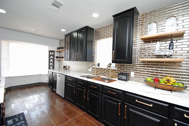 kitchen with sink, tasteful backsplash, dark tile patterned flooring, dishwasher, and light stone countertops