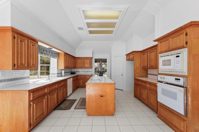 kitchen with vaulted ceiling, tasteful backsplash, a center island, light tile patterned floors, and white appliances