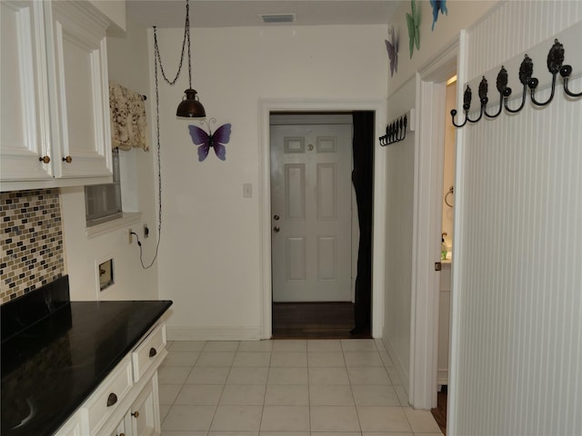 kitchen with light tile patterned flooring, decorative light fixtures, tasteful backsplash, and white cabinets