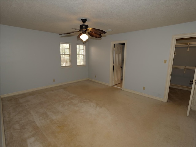 empty room with ceiling fan, light colored carpet, and a textured ceiling