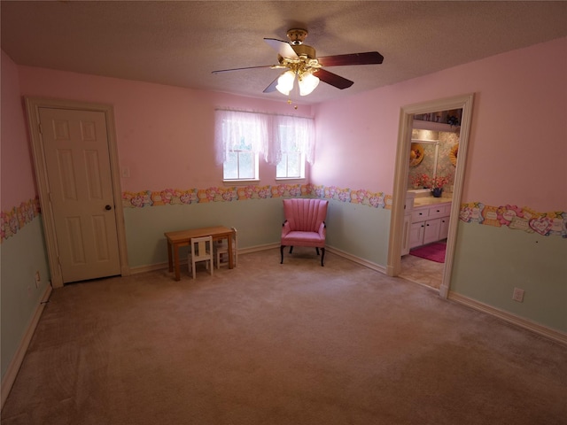 living area with ceiling fan, light carpet, and a textured ceiling