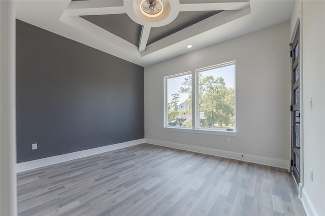 spare room with ceiling fan, a tray ceiling, light wood-style flooring, and baseboards