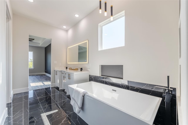 bathroom with recessed lighting, baseboards, marble finish floor, a soaking tub, and double vanity