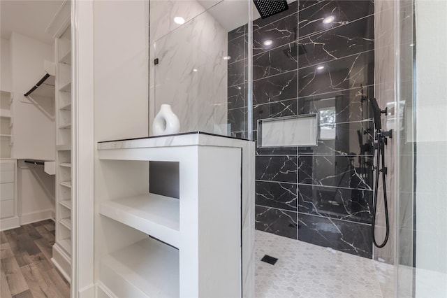 full bath with wood finished floors, a walk in closet, and a marble finish shower