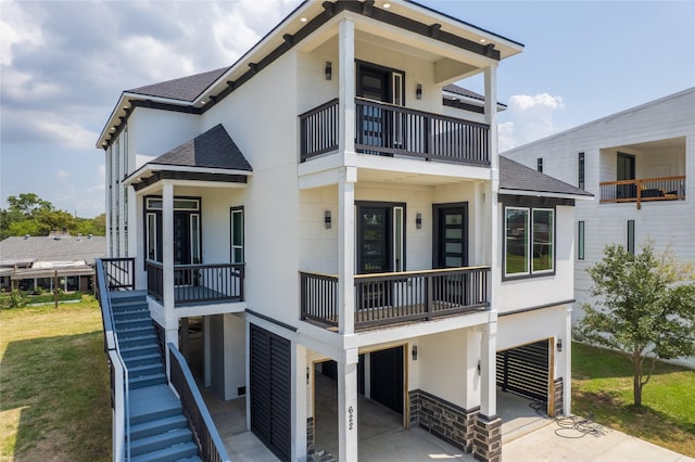 view of front facade featuring stairs, concrete driveway, a shingled roof, and stucco siding