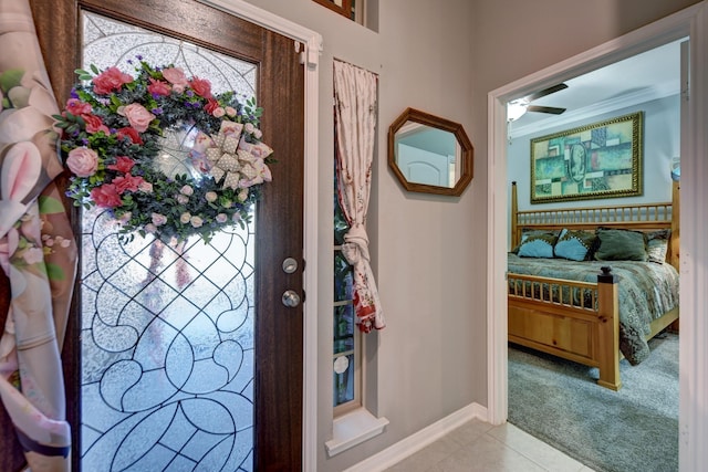 tiled foyer entrance featuring crown molding and ceiling fan