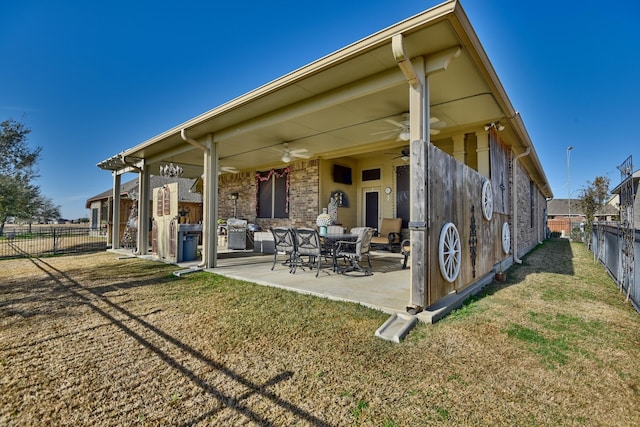 back of property with a lawn, a patio, and ceiling fan