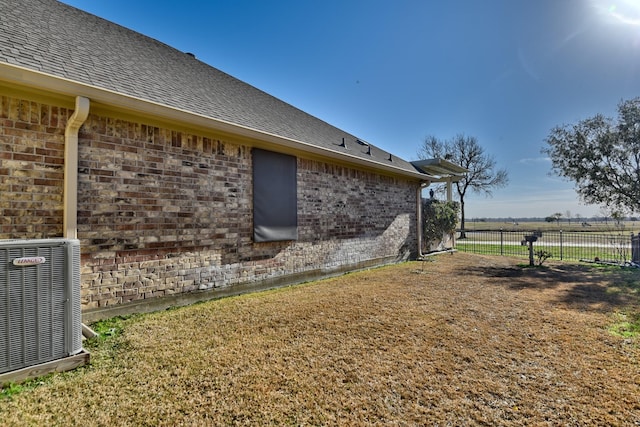 view of property exterior with a rural view, a lawn, and central air condition unit