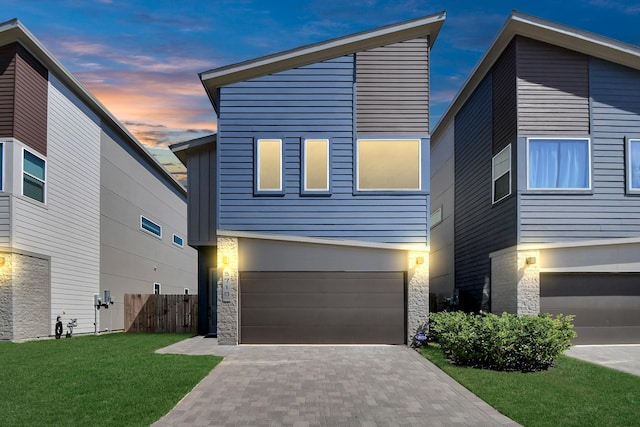 contemporary home featuring a garage and a lawn