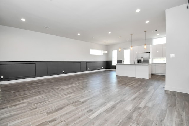 unfurnished living room featuring sink and light hardwood / wood-style floors