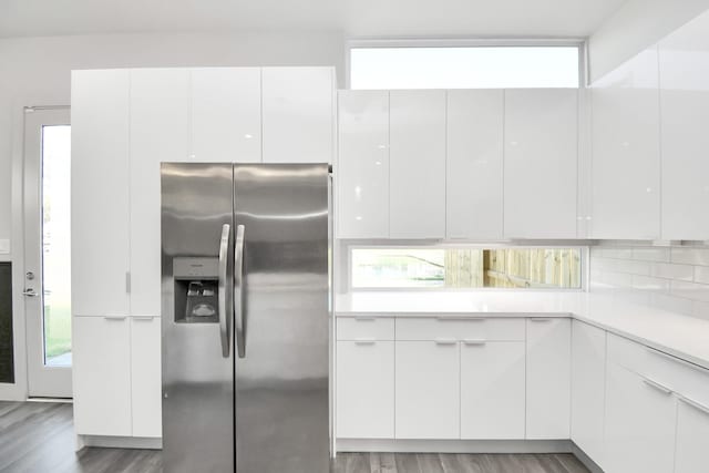 kitchen featuring white cabinetry, stainless steel refrigerator with ice dispenser, light wood-type flooring, and decorative backsplash