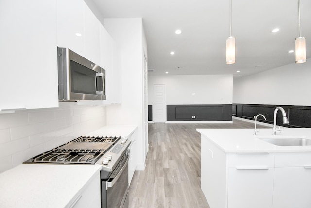 kitchen with pendant lighting, white cabinetry, stainless steel appliances, and sink