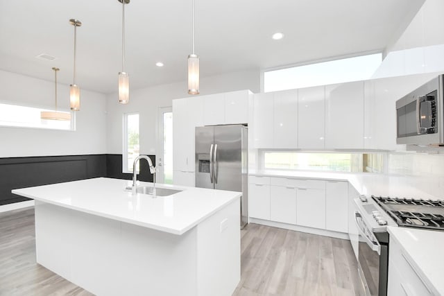 kitchen featuring stainless steel appliances, white cabinetry, sink, and pendant lighting