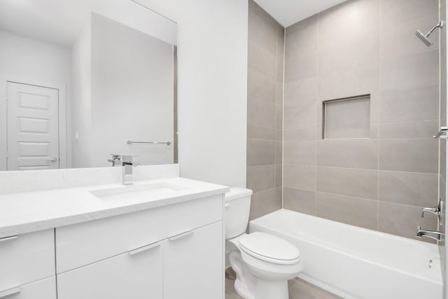 full bathroom featuring vanity, tiled shower / bath combo, and toilet