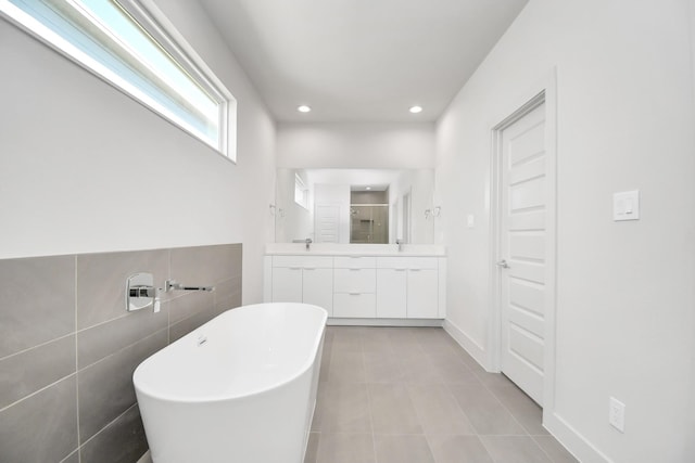 bathroom featuring independent shower and bath, vanity, tile patterned flooring, and tile walls