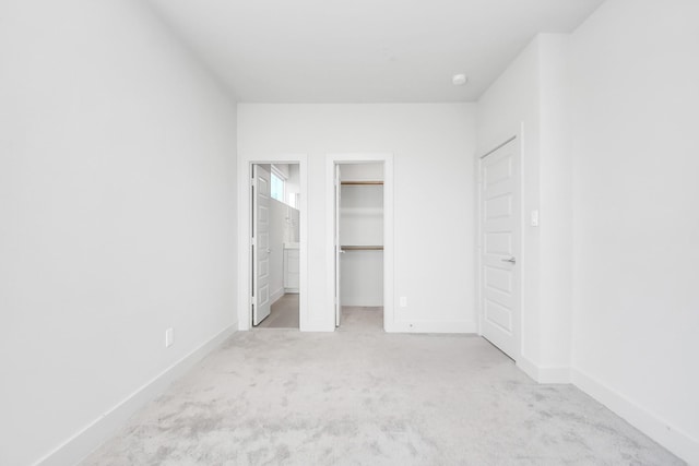 unfurnished bedroom with light colored carpet and a spacious closet