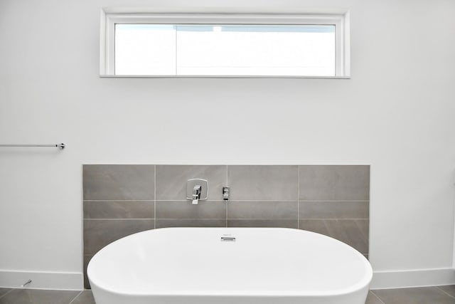 bathroom with tile patterned flooring, a healthy amount of sunlight, and a washtub