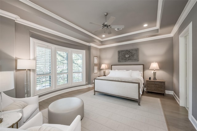 bedroom with ceiling fan, ornamental molding, a tray ceiling, and light hardwood / wood-style floors