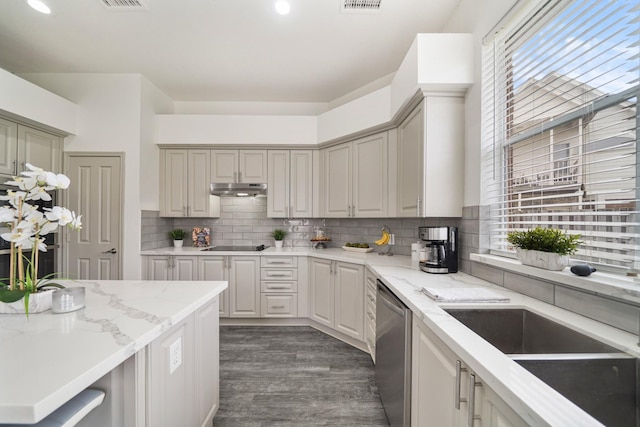 kitchen featuring tasteful backsplash, dark hardwood / wood-style flooring, dishwasher, black electric stovetop, and light stone countertops