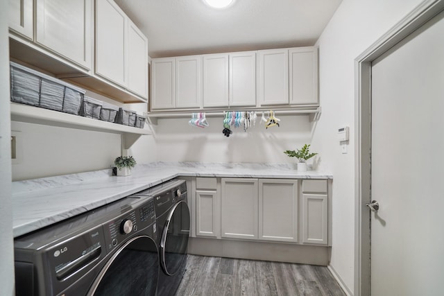 clothes washing area with cabinets, wood-type flooring, and separate washer and dryer